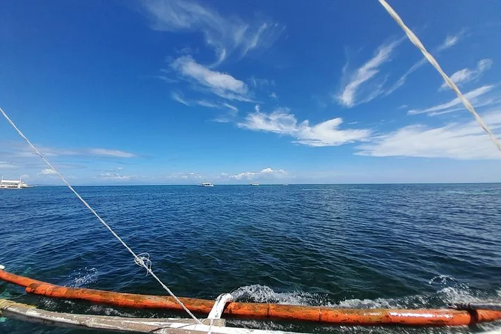Vista de aguas azules del océano y botes a lo lejos desde un bote de balancín