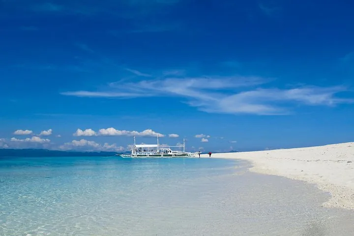 Eine weiße Sandbank mit einem Boot, das in klarem blauem Wasser vertäut ist
