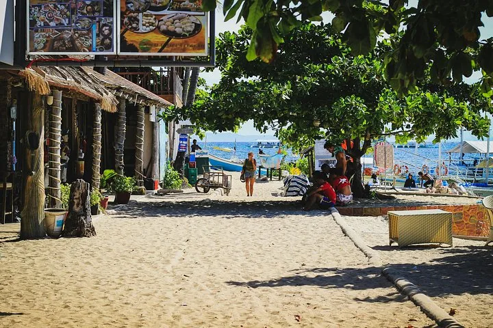 A sandy path lined with shops and trees near the beach