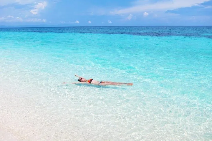 Frau, die im kristallklaren türkisfarbenen Wasser auf der Insel Kalanggaman treibt