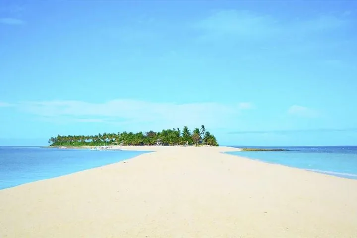Ampio banco di sabbia bianca che si estende verso un'isola orlata di palme